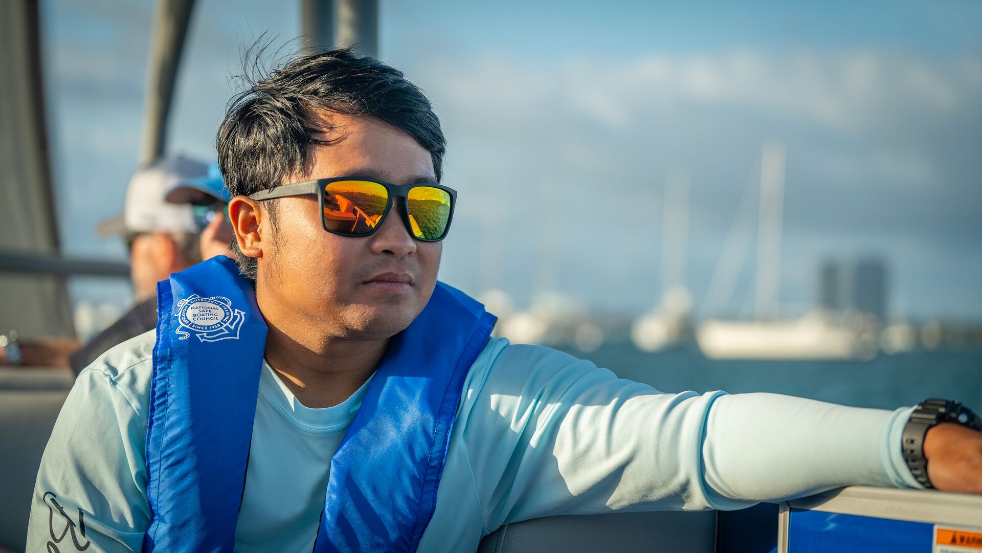 A guy on a boat wearing an inflatable PFD.