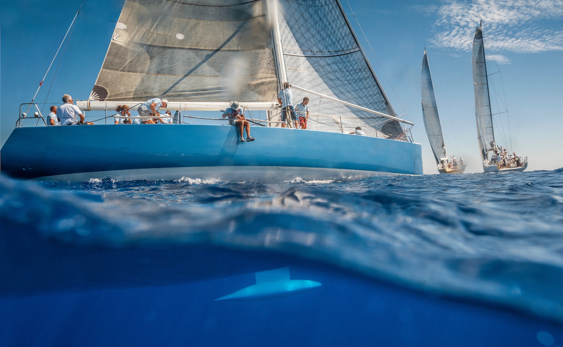 People on a sailboat in the water showing the boat keel underwater. 